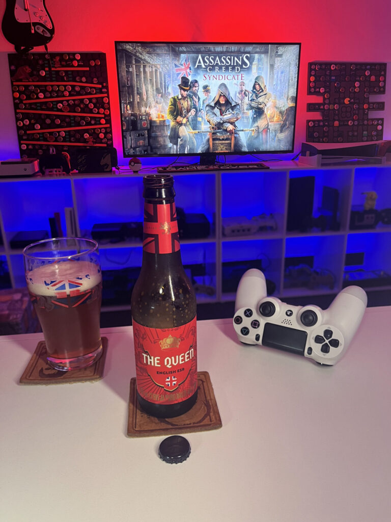 Cerveja The Queen da Caixa da Alegria ao lado de Assassin's Creed Syndicate