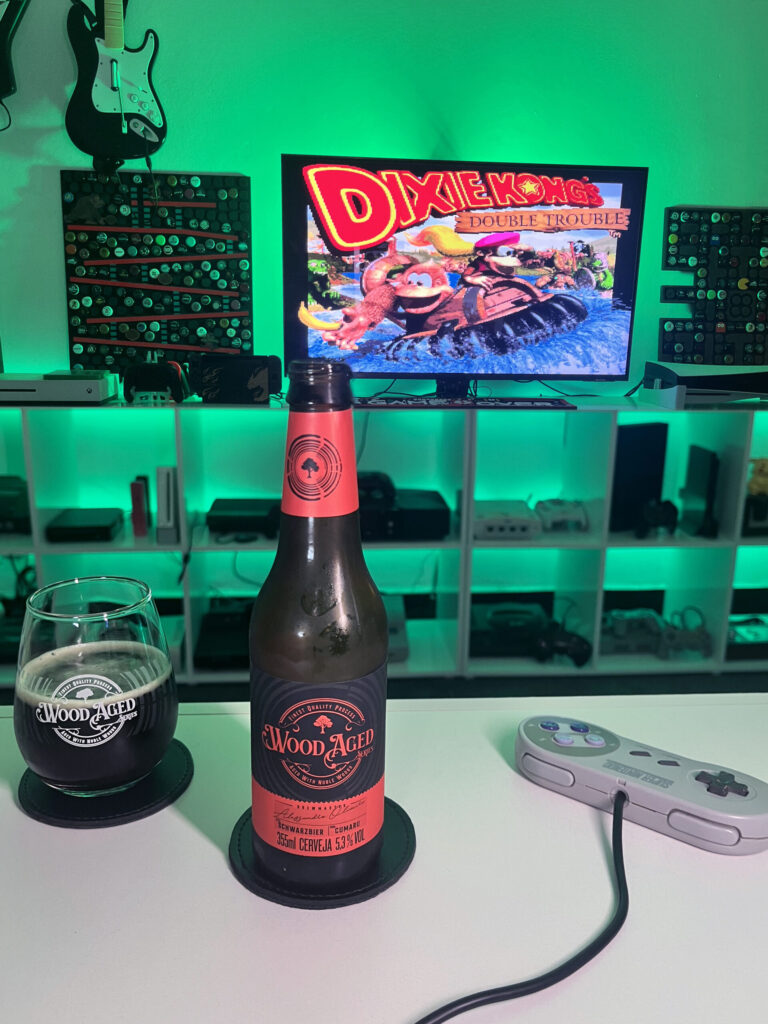 Cerveja Schwarzbier Wood Aged da Caixa da Alegria ao lado de Donkey Kong Country 3
