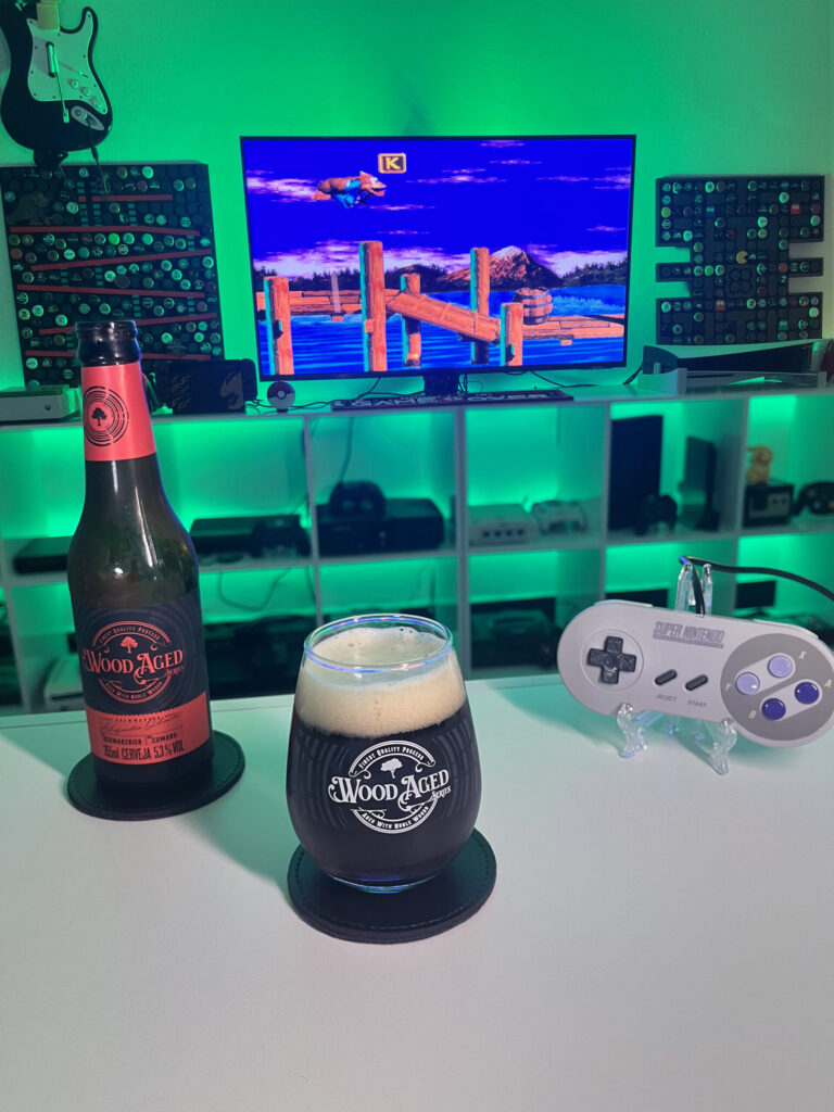 Cerveja Schwarzbier Wood Aged da Caixa da Alegria ao lado de Donkey Kong Country 3
