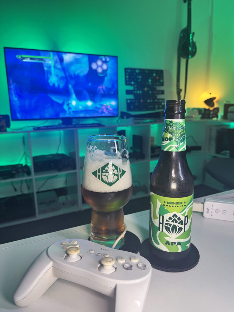 Cerveja APA ao lado de Green Lantern Rise of the Manhunters no Wii em clima de heroi
