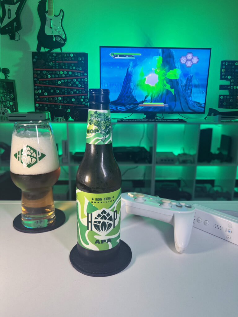 Cerveja APA ao lado de Green Lantern Rise of the Manhunters no Wii em clima de heroi