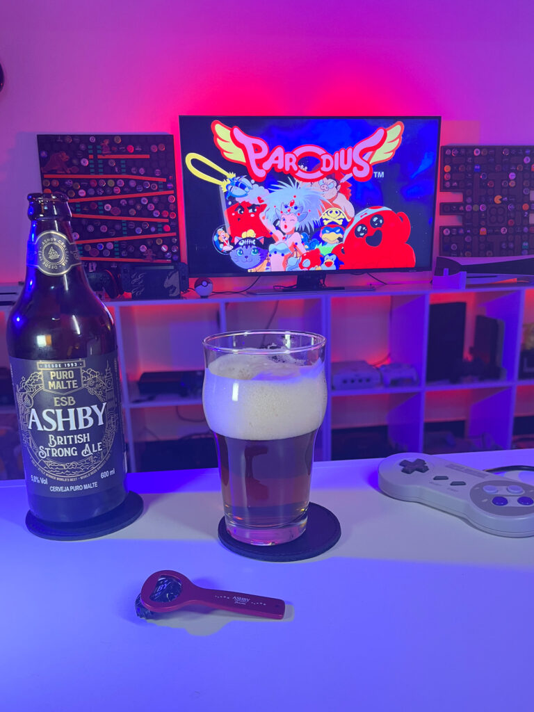 Cerveja British Strong Ale ao lado de Parodius no Super Nintendo em clima de humor e ação.