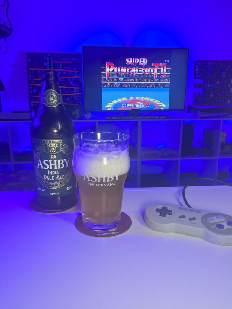 Cerveja IPA dourada com espuma branca ao lado de gameplay de Super Punch-Out!! no Super Nintendo em clima retrô.