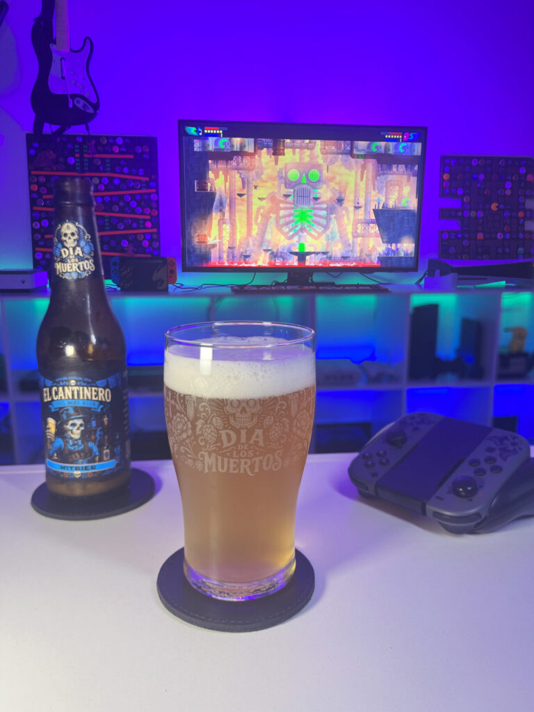 Cerveja Witbier palha turva ao lado de Guacamelee Super Turbo Championship Edition no Nintendo Switch em clima de Dia de los Muertos.