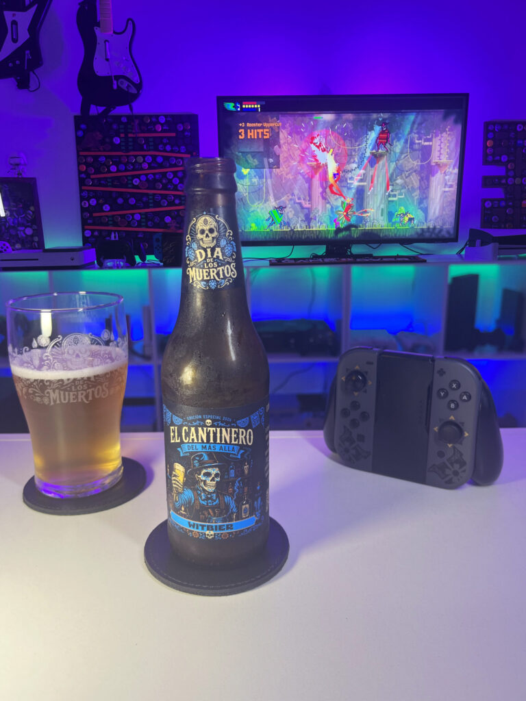 Cerveja Witbier palha turva ao lado de Guacamelee Super Turbo Championship Edition no Nintendo Switch em clima de Dia de los Muertos.