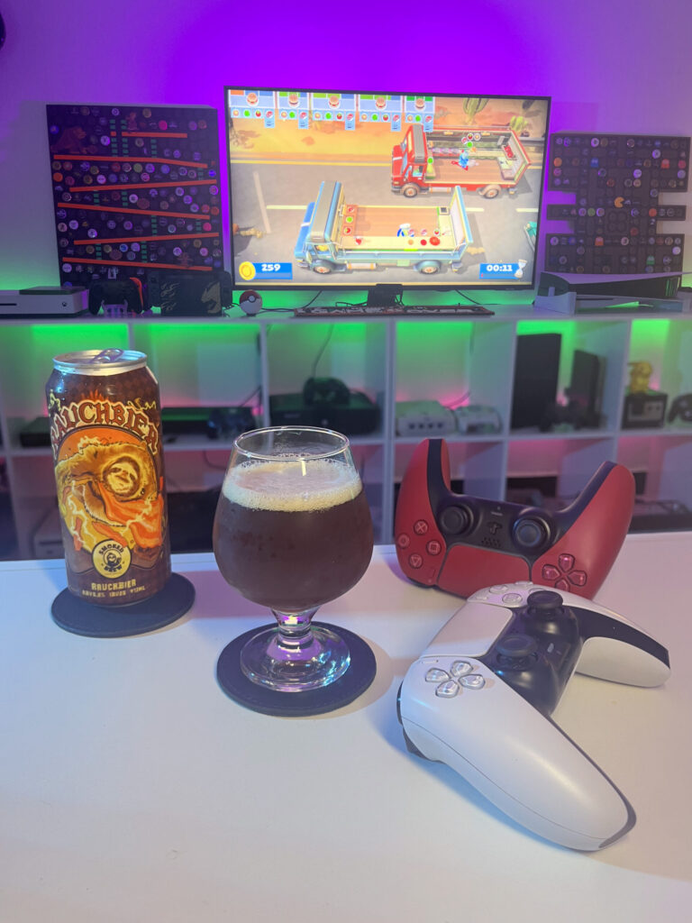 Cerveja escura estilo Rauchbier ao lado de gameplay cooperativo de Overcooked no PS5 com dois controles na mesa.