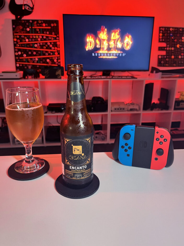 Cerveja Pilsen dourada ao lado de tela inicial de Diablo II Resurrected com personagem Bruxo selecionado.