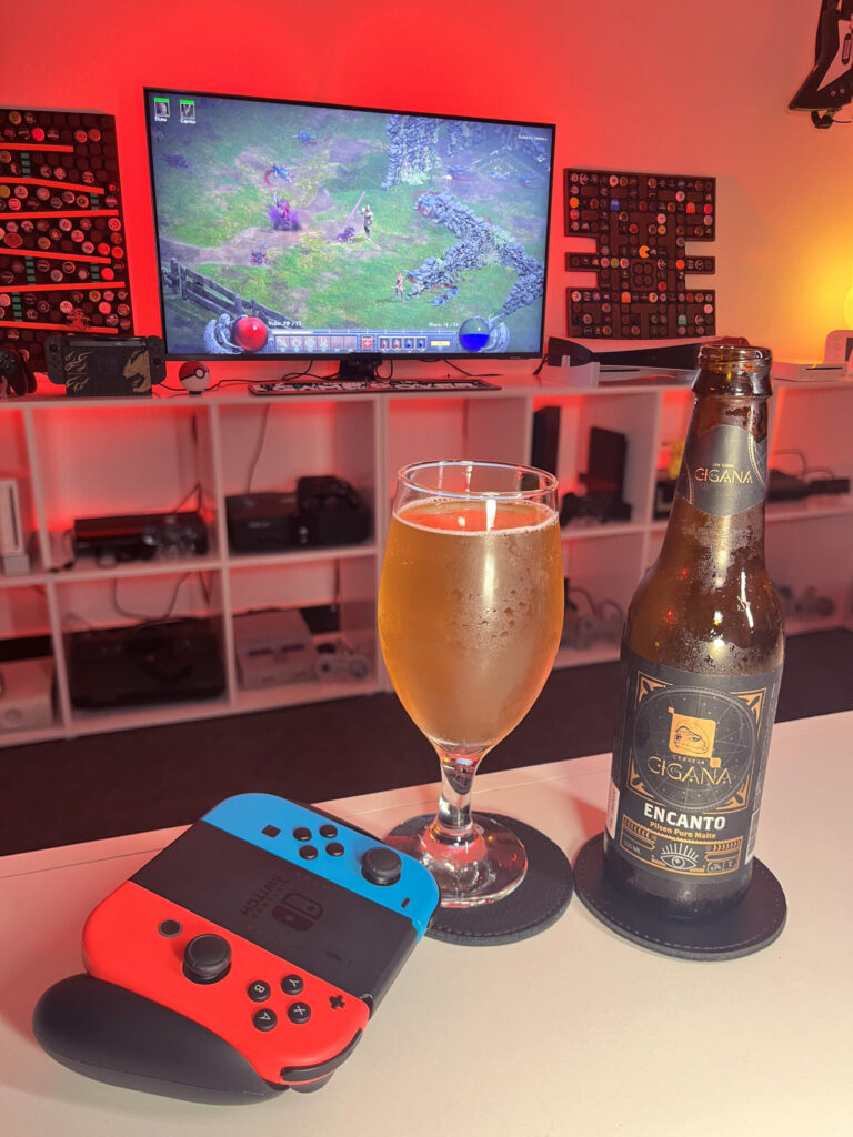Cerveja Pilsen dourada ao lado de tela inicial de Diablo II Resurrected com personagem Bruxo selecionado.