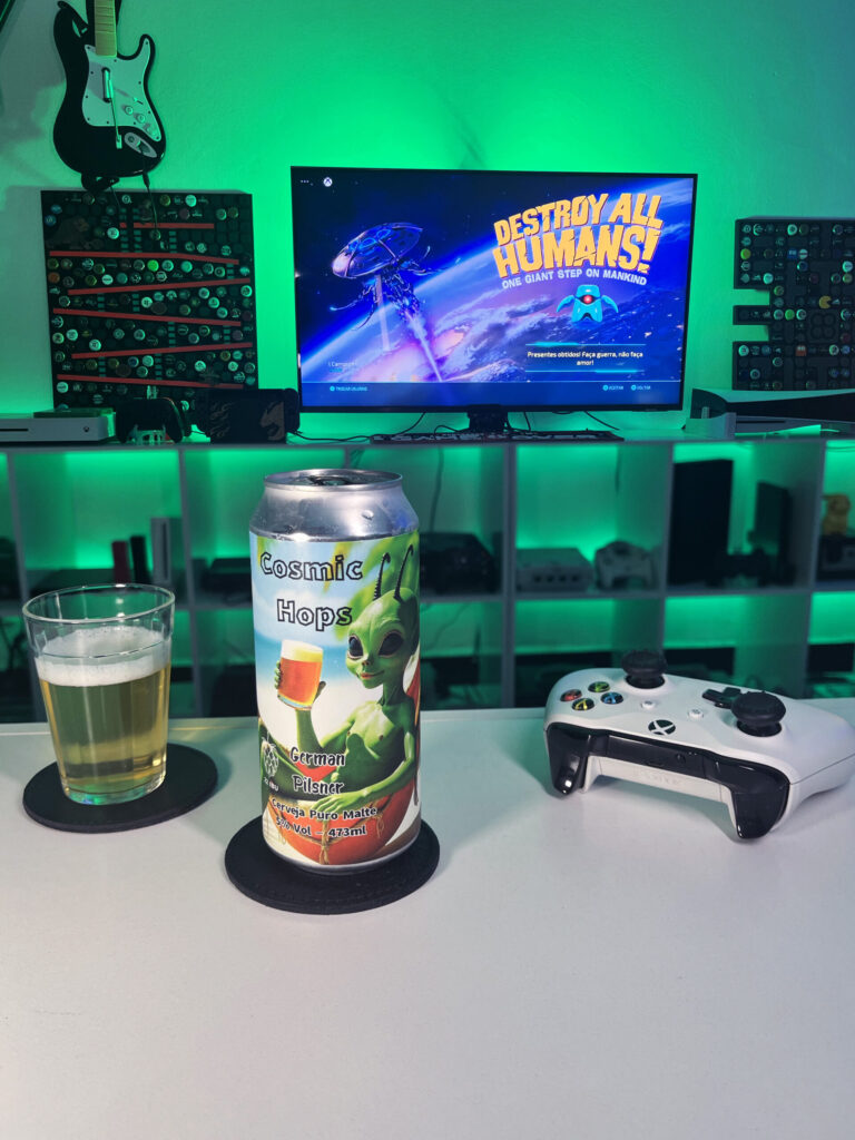 Cerveja German Pilsner amarelo claro ao lado de Destroy All Humans no Xbox One em clima de invasão alienígena.