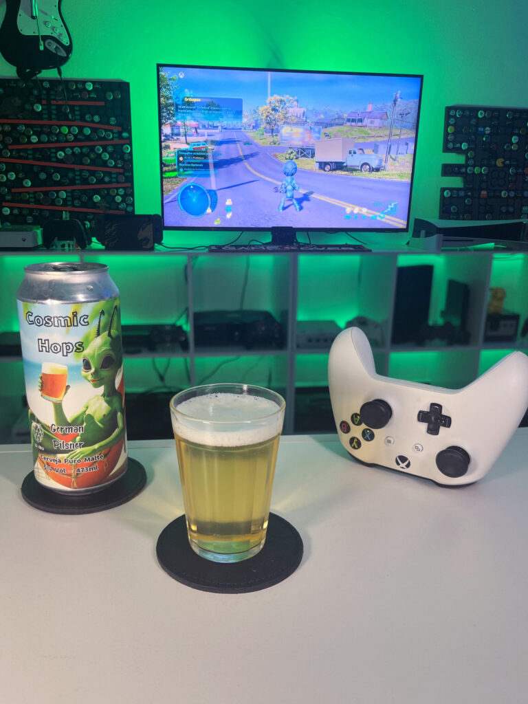 Cerveja German Pilsner amarelo claro ao lado de Destroy All Humans no Xbox One em clima de invasão alienígena.