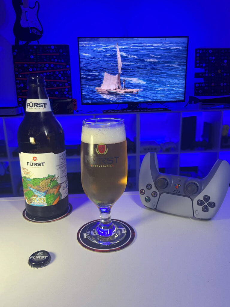 Cerveja Pilsen dourada e cristalina ao lado de Assassin's Creed Black Flag Resynced no PS5 em clima de pirataria.
