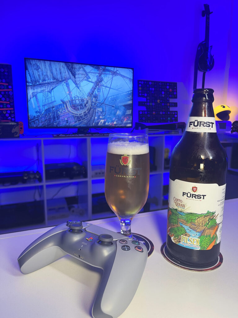 Cerveja Pilsen dourada e cristalina ao lado de Assassin's Creed Black Flag Resynced no PS5 em clima de pirataria.
