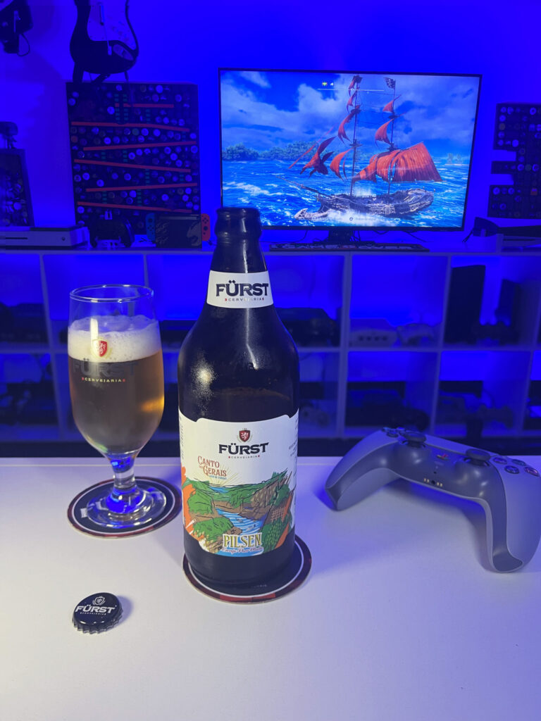 Cerveja Pilsen dourada e cristalina ao lado de Assassin's Creed Black Flag Resynced no PS5 em clima de pirataria.
