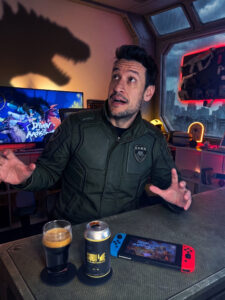 Cerveja Russian Imperial Stout preta ao lado de Dawn of the Monsters no Nintendo Switch em clima de batalha de titãs.