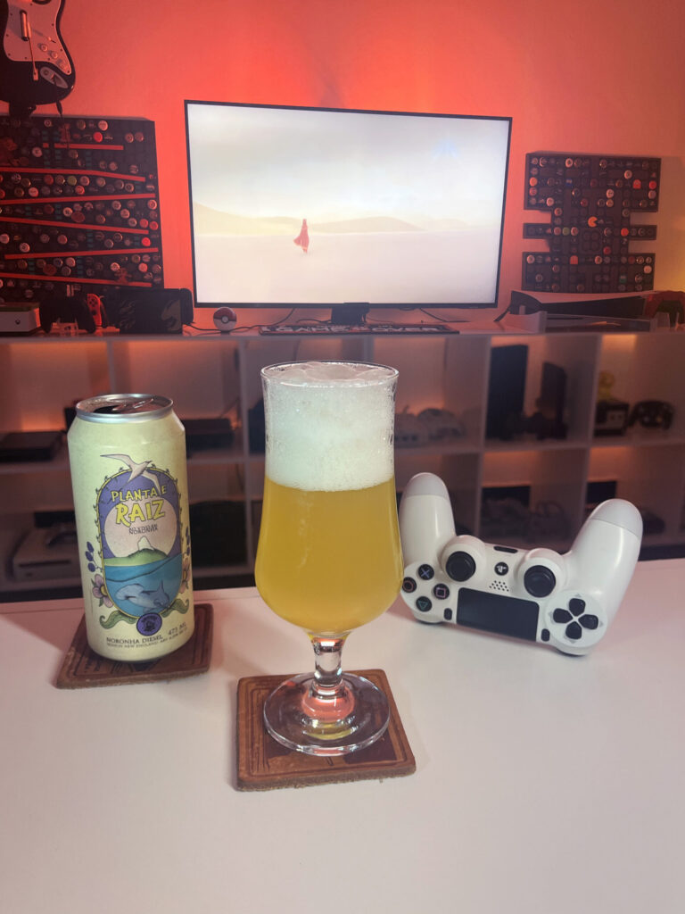 Cerveja Session New England amarela turva ao lado de Journey no PS4 em clima de travessia pelo deserto.