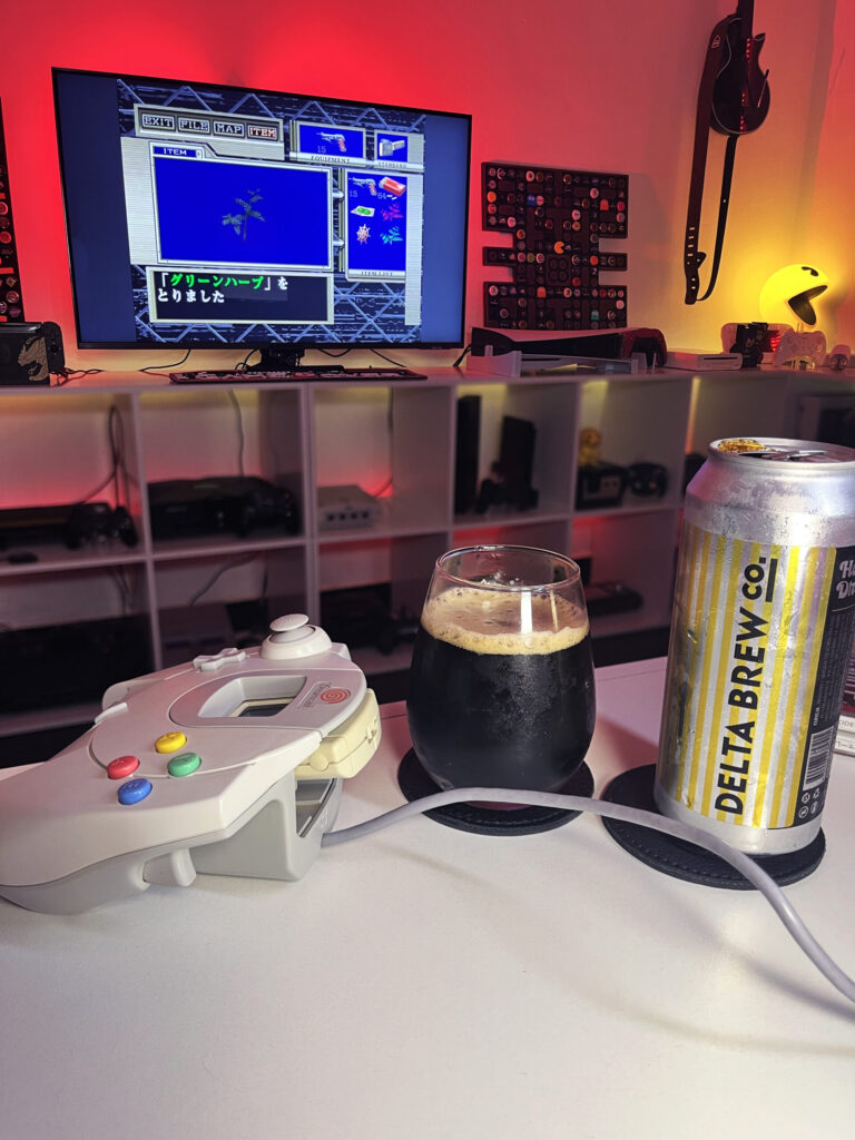 Cerveja Hazelnut Dreams negra com espuma marrom clara, ao lado de Biohazard Code: Veronica no Dreamcast.