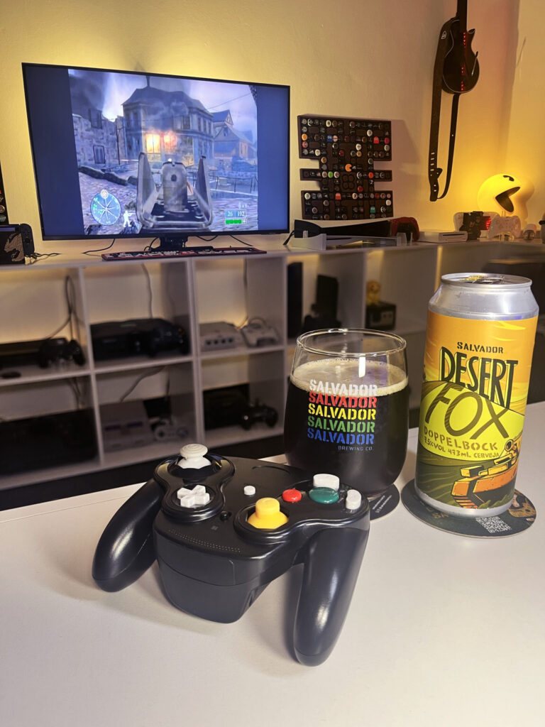 Cerveja Desert Fox cor de carvalho com nuances rubis, ao lado de Call of Duty 2: Big Red One no GameCube.